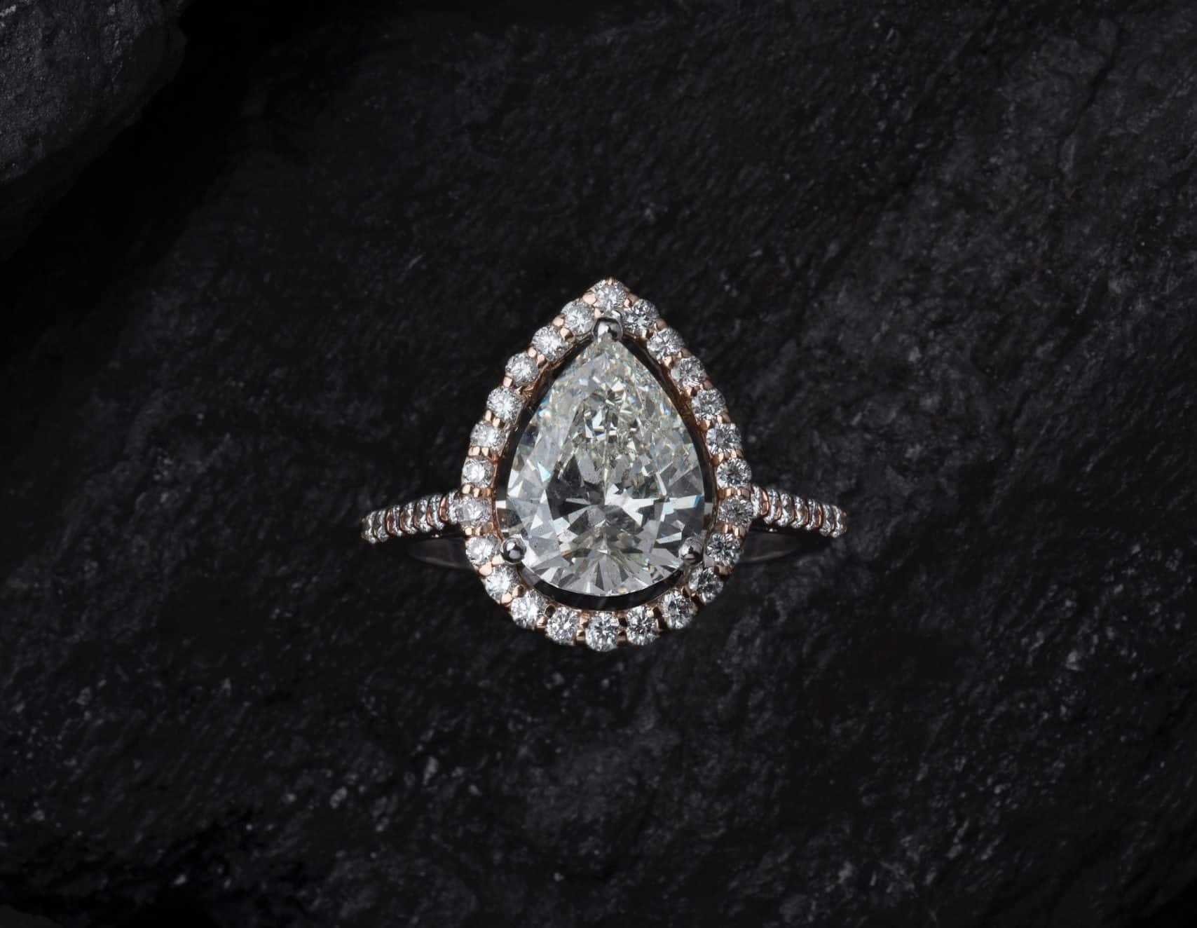 A pear shaped diamond ring on a black background