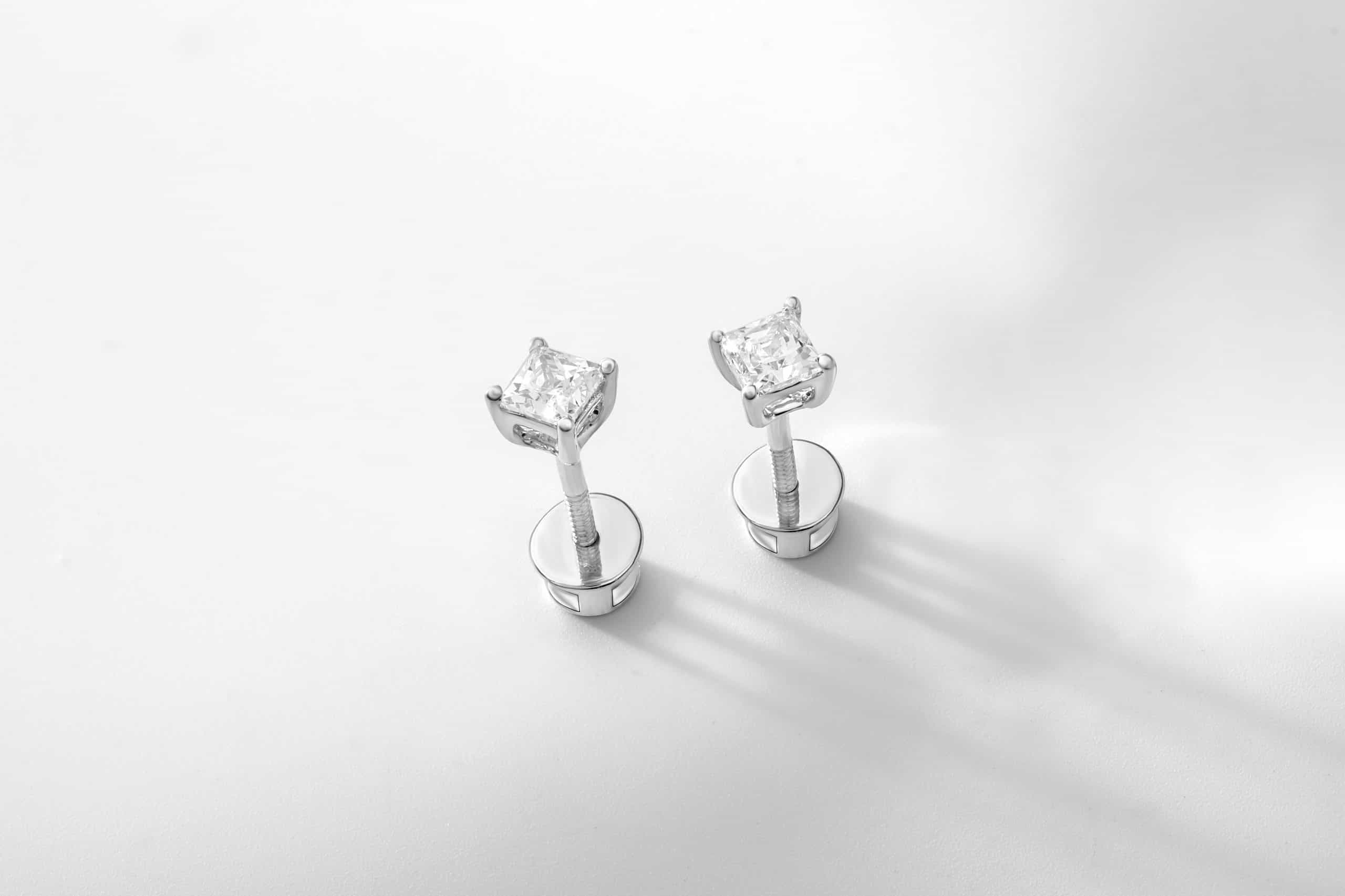 Two diamond stud earrings on a white surface