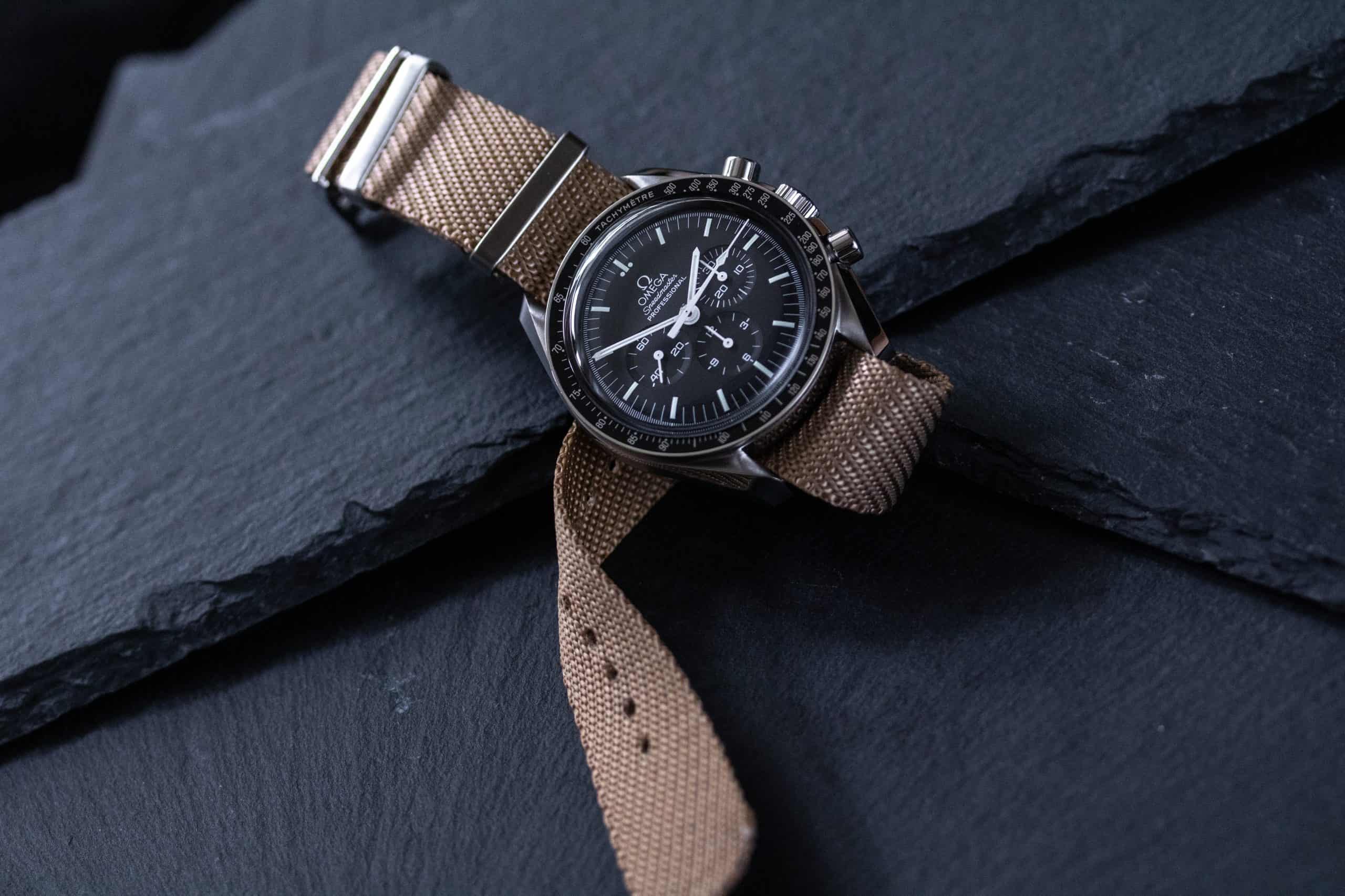 A watch laying on a stone surface with a strap